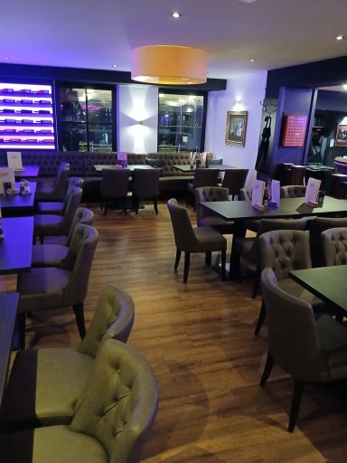 Moderne Restaurant-Innenansicht mit Holzboden und stilvollen Stühlen und Tischen.