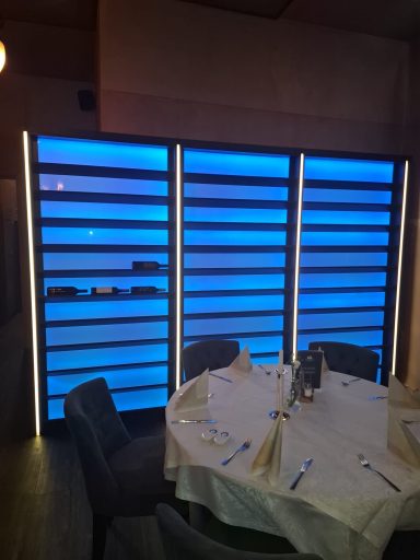 Ein rund gedeckter Tisch vor einer blauen beleuchteten Wand im Restaurant.