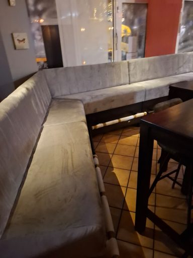 Bequeme Sitzbank in einem Restaurant mit Holzdetails und Fliesenboden.