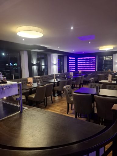 Elegantes Restaurant mit modernen Tischen, sanfter Beleuchtung und einem Weinschrank.