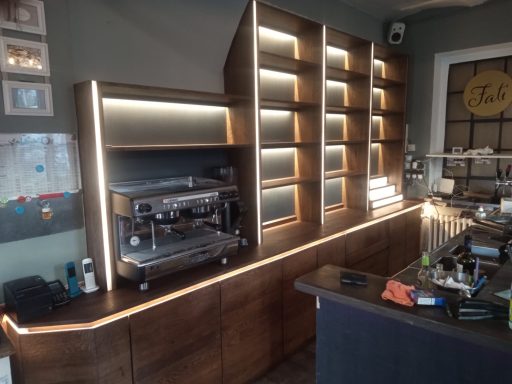 Holzregal mit Beleuchtung und Kaffeemaschine in einem modernen Café.