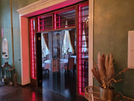 Eingangstür mit roten Akzenten und elegantem Restaurantambiente im Hintergrund.
