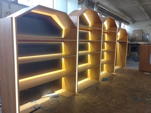 Holzbücherregale mit LED-Beleuchtung in einem Werkstattumfeld.