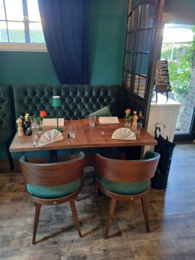 Eleganter Tisch mit zwei Stühlen in einem gemütlichen Restaurant, umgeben von grünen Wänden.