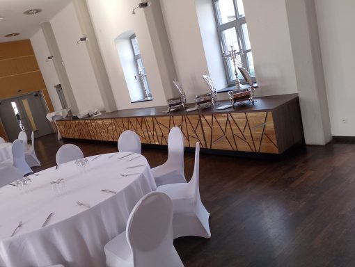 Eleganter Veranstaltungsraum mit runder Tafel und Buffetbereich.