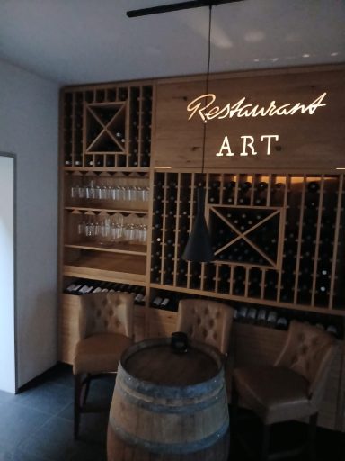 Holzdekorierte Wand mit Weinfässern und Gläsern, Beschriftung "Restaurant ART".