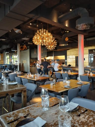 Moderne Restaurant mit Holzdekoren, stilvollen Lampen und Gästen an Tischen.