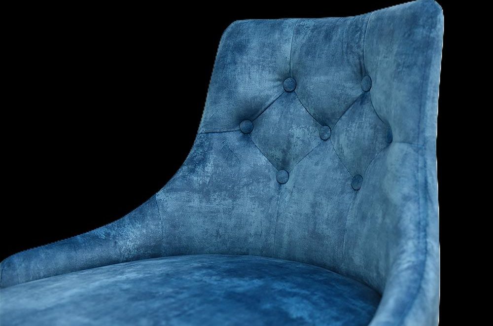Bequemer, blauer Sessel mit gepolsterter Rückenlehne und Knopfdetails.