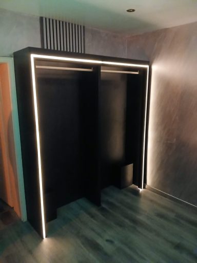 Schwarzer Kleiderschrank mit LED-Beleuchtung und offenem Innenraum.