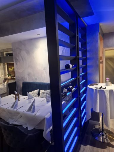 Ein moderner Restaurantbereich mit blauer Akzentbeleuchtung und eleganter Tischdekoration.