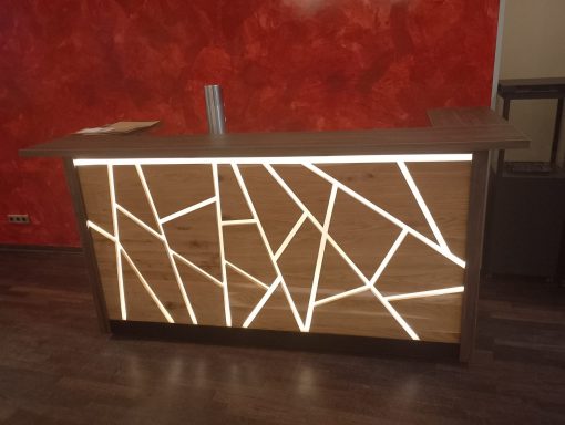 Moderne Empfangstheke aus Holz mit geometrischem Muster und indirekter Beleuchtung.