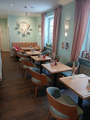 Gemütliches Restaurant mit Holzstühlen, Tischen und hellblauen Wänden.